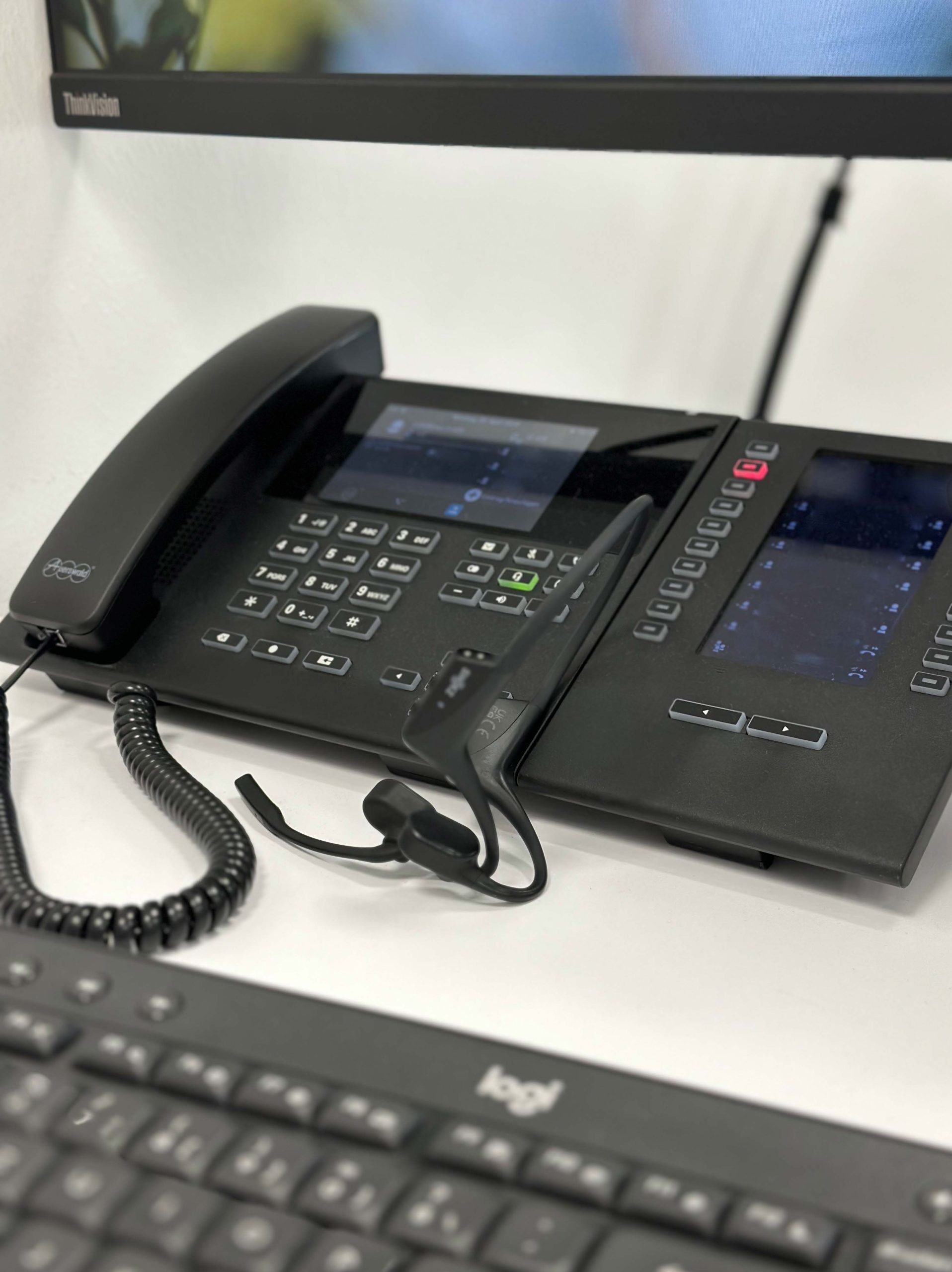 Ein Telefon in unserem Unternehmen ist mit einem Headset und einer Tastatur ausgestattet. Diese Ausstattung unterstreicht die professionelle und effiziente Arbeitsumgebung, die Kommunikation und Produktivität fördert.